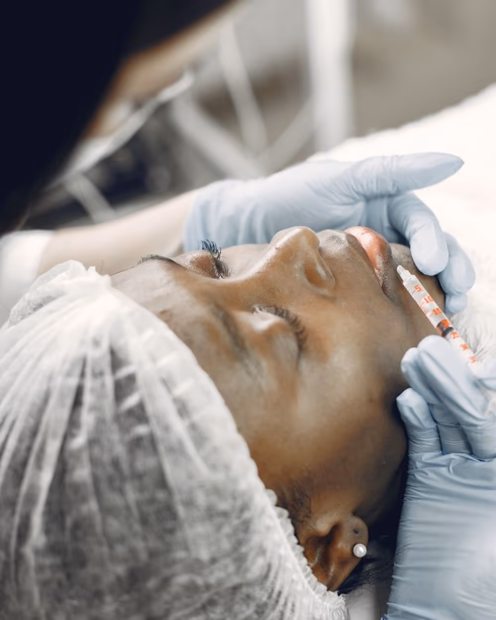 A relaxed client receiving a precise aesthetic treatment, gloved hands in fine control
